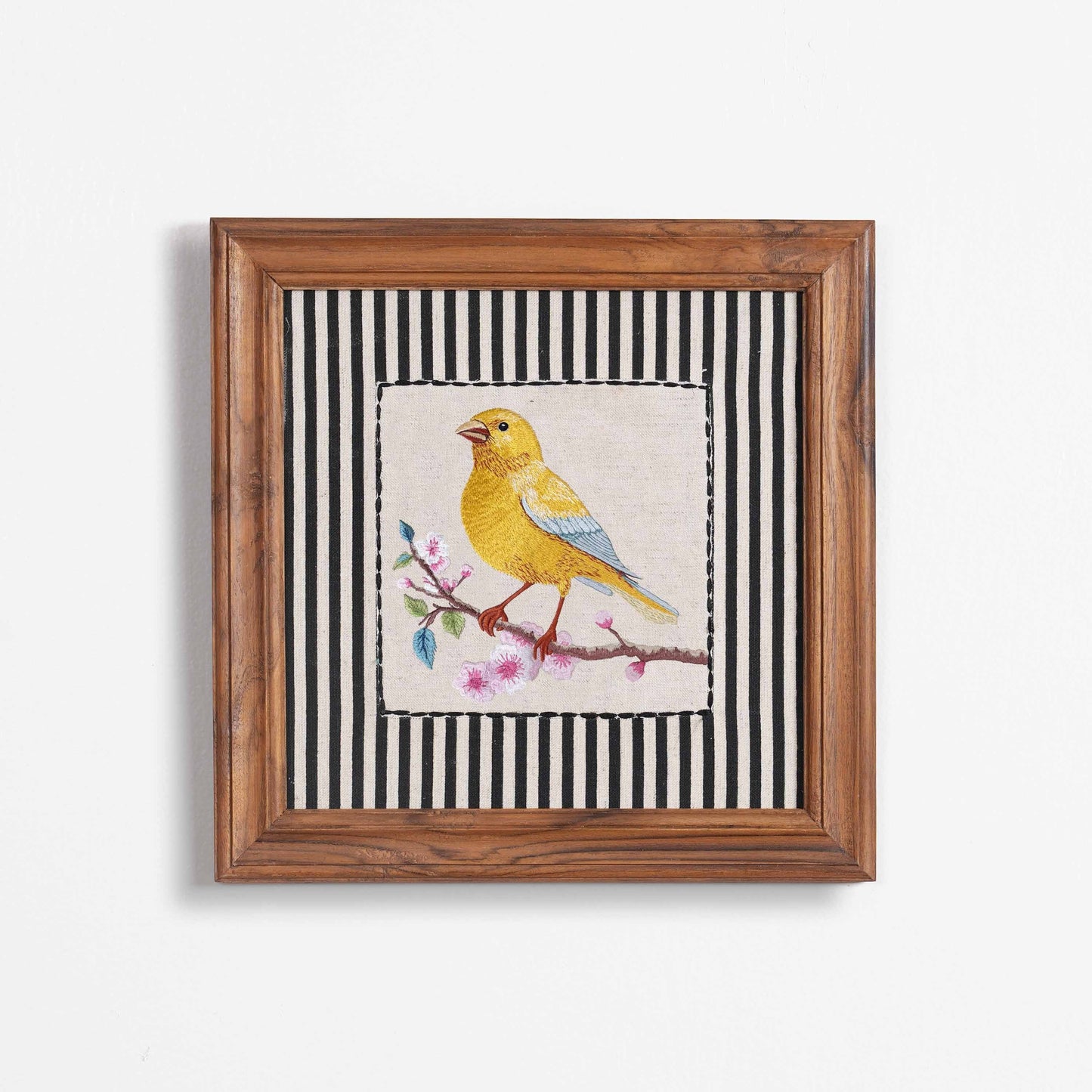 Vliving framed embroidered canary yellow bird wall art with pink blossoms on a linen fabric with black and white striped background.