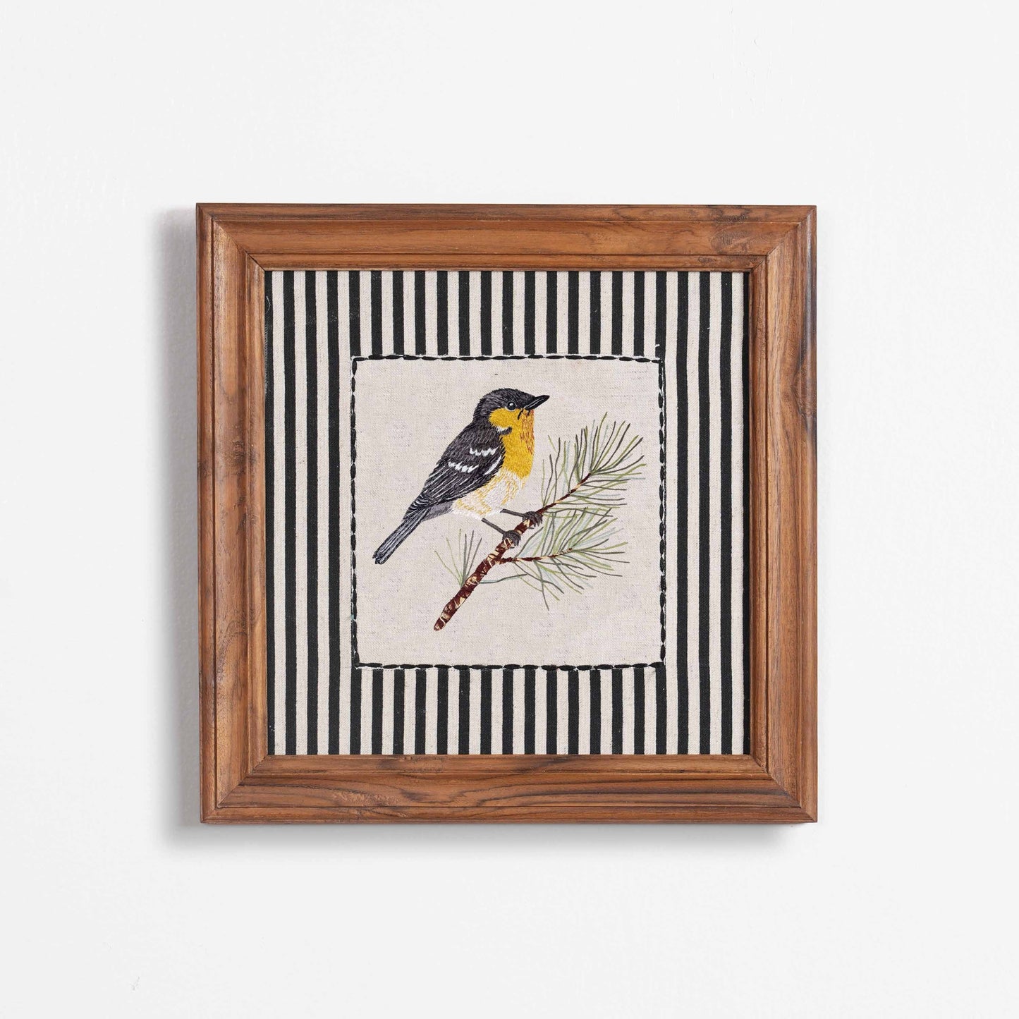 Vliving framed embroidered yellow and grey bird on a pine branch with black and white striped background. Linen art.