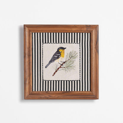 Vliving framed embroidered yellow and grey bird on a pine branch with black and white striped background. Linen art.