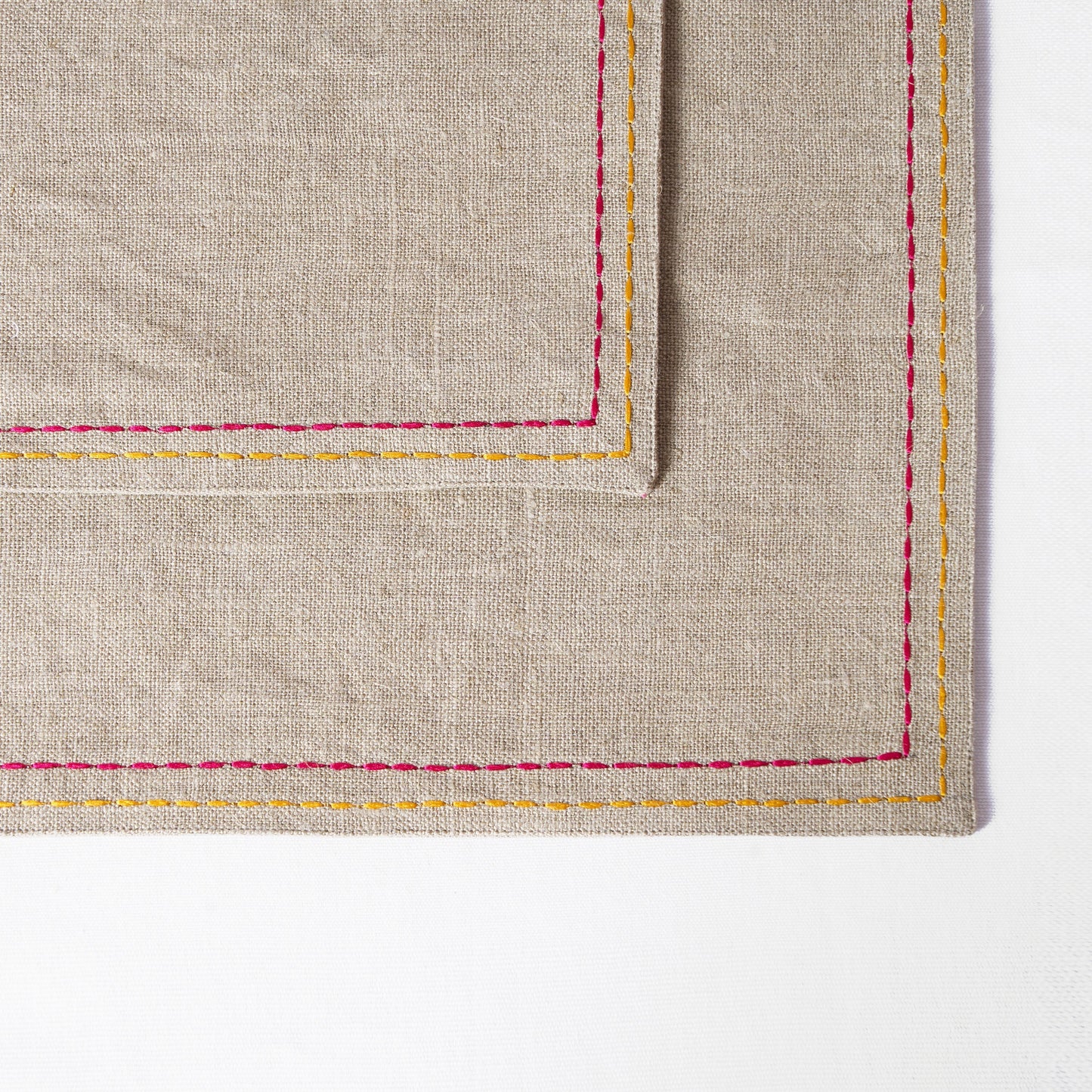 Vliving linen placemat with multicolour silk thread embroidery in rice stitch along the border.