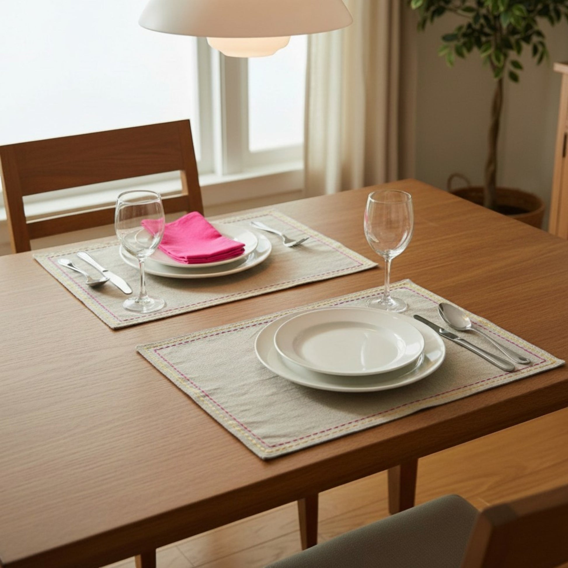 Vliving embroidered linen placemats with multicolour silk thread rice stitch embroidery. Set of 2 shown on a wooden table.