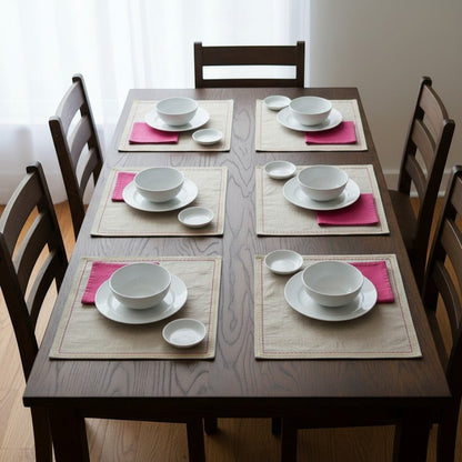 Vliving embroidered linen placemats with pink napkins and white dishes on a dark wood table.