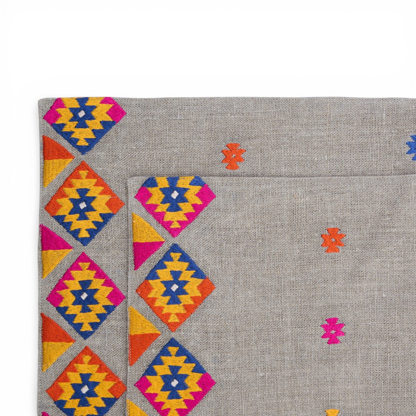Vliving grey linen table mats with multicolour kilim embroidery in geometric diamond patterns.