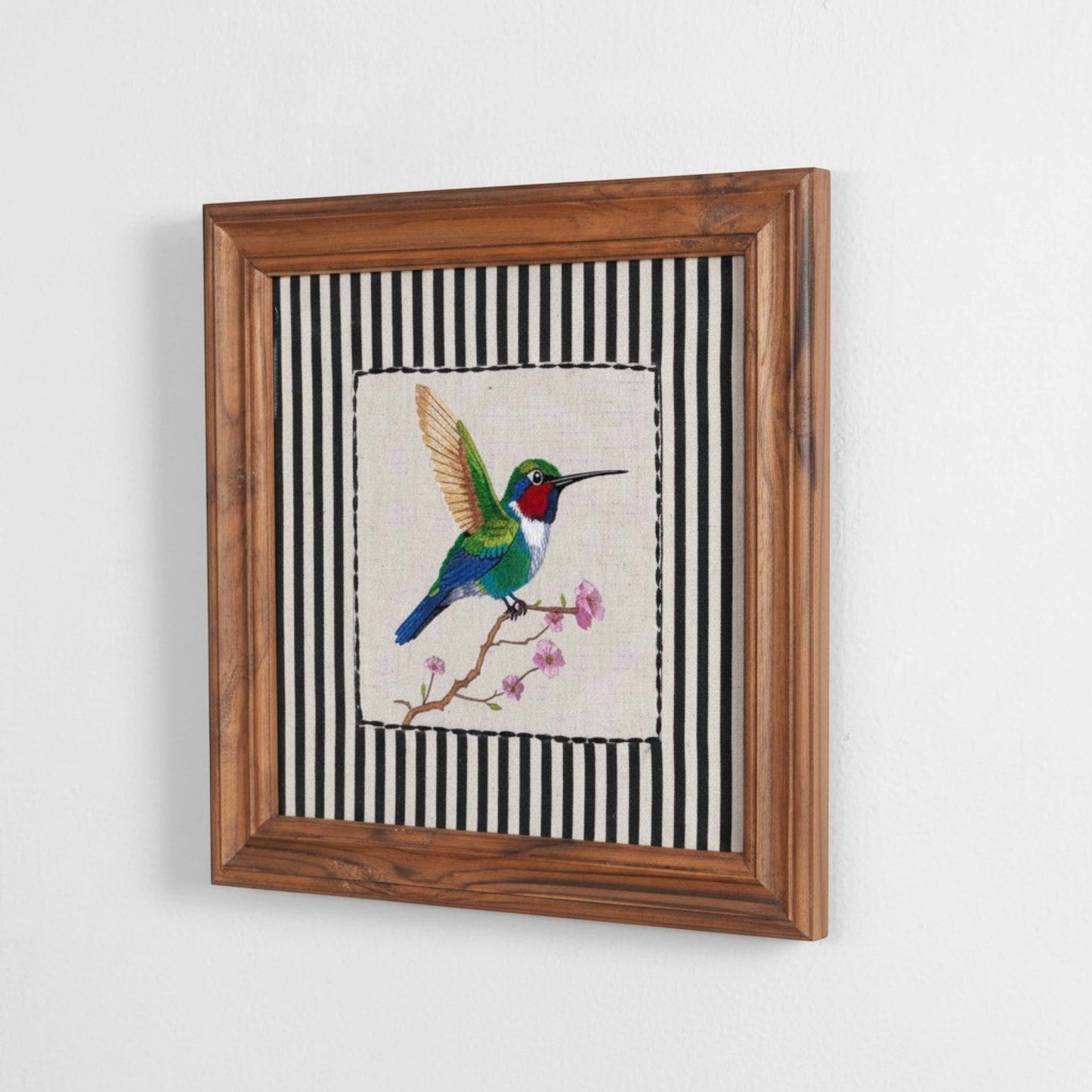 Vliving framed wall art featuring a green hummingbird with red and white accents on a branch with pink flowers, set against a black and white striped background.